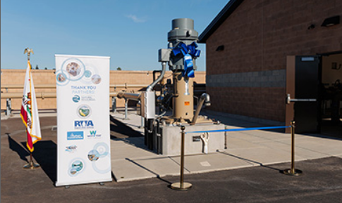 A newly commissioned SSWD wellhead with a blue ribbon tied around it at a dedication ceremony.